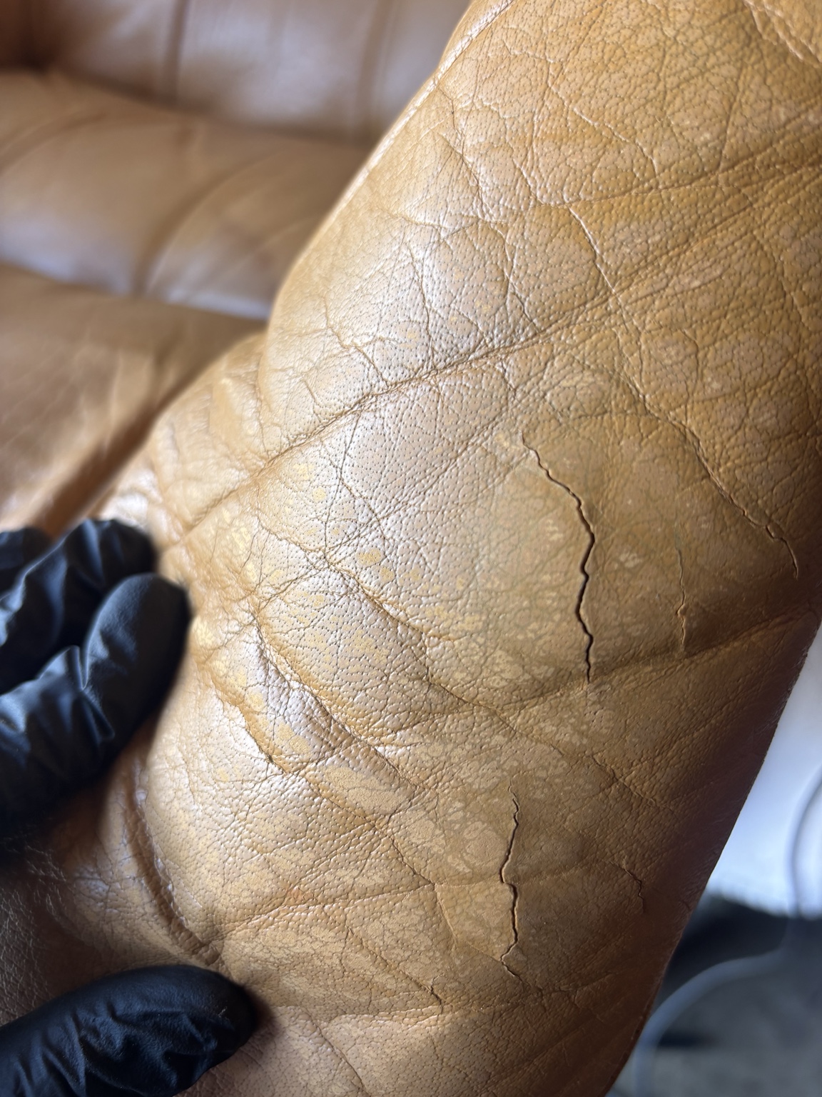 Close view of cracks in tan leather before repair
