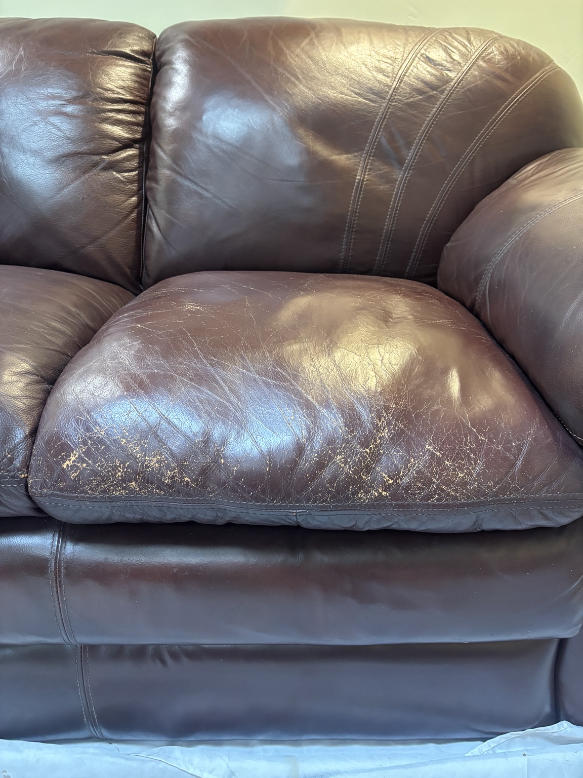 Scuffed and worn leather seat cushion before repair
